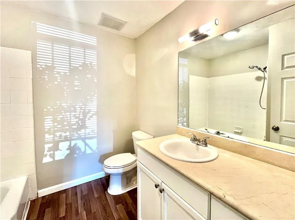 Bathroom featuring vanity, dark wood finished floors, and shower / washtub combination