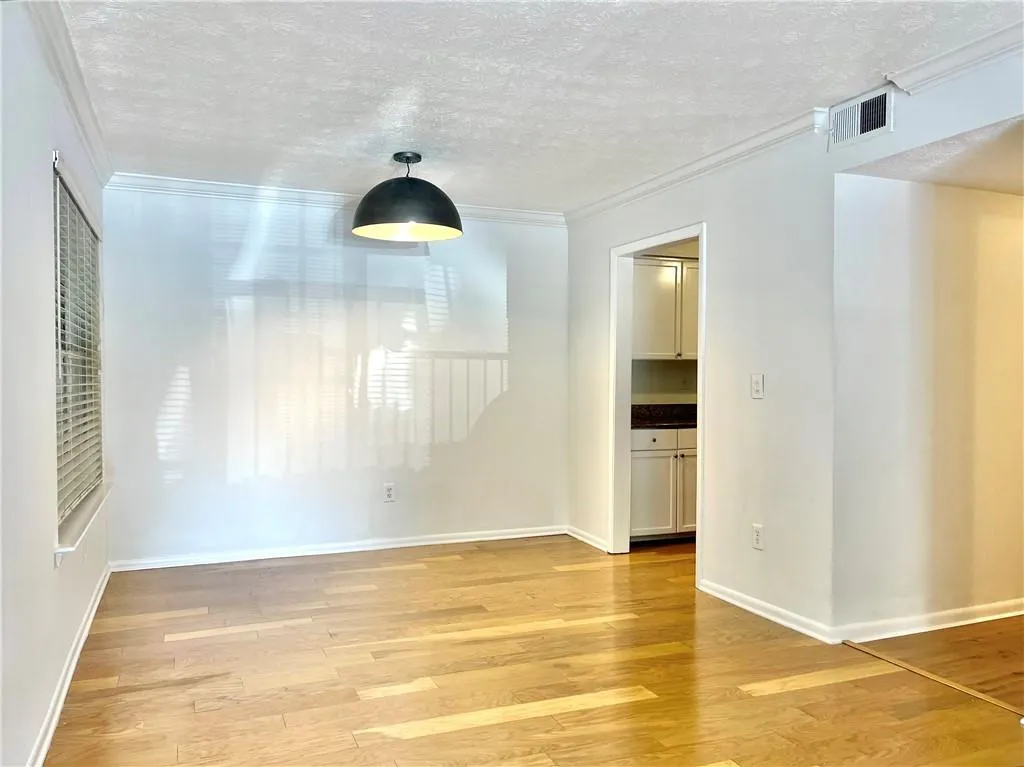 Unfurnished dining area with crown molding, a textured ceiling, and light wood finished floors