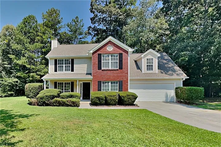 Two-story exterior with brick and siding facade, covered front entry, attached two-car garage, and established landscaping