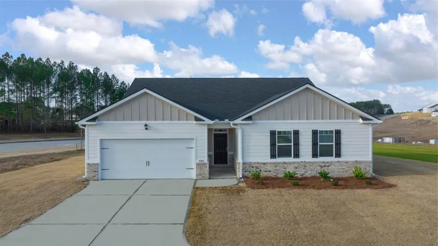 Craftsman-style home featuring board and batten siding, driveway, a garage, brick siding, and a front yard