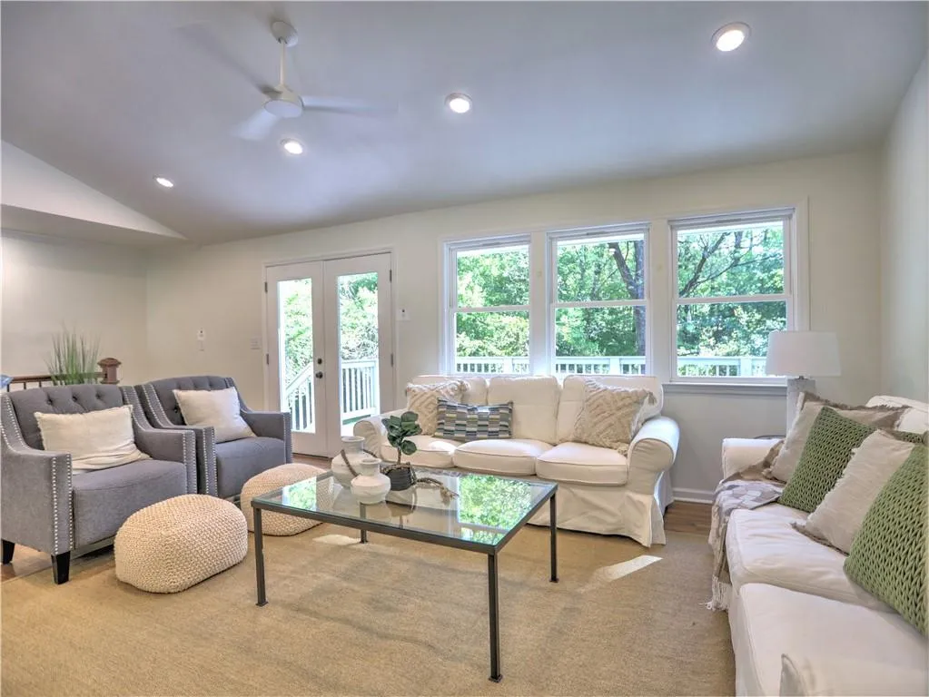 Living room with ceiling fan, french doors, and vaulted ceiling
