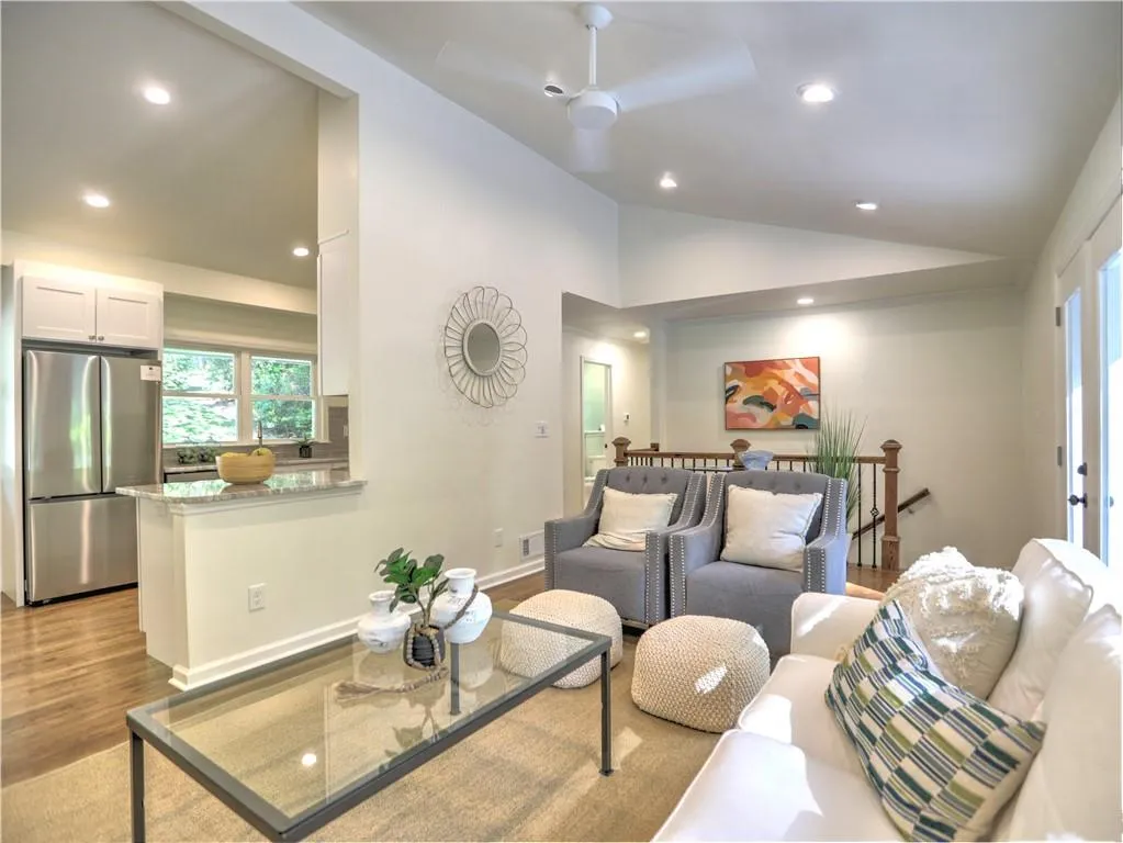 Living room featuring lofted ceiling, ceiling fan, and light wood-type flooring
