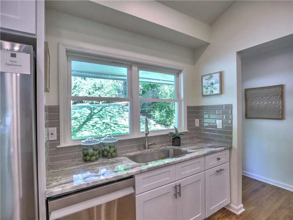 Kitchen with sink, tasteful backsplash, stainless steel appliances, dark hardwood / wood-style floors, and light stone countertops
