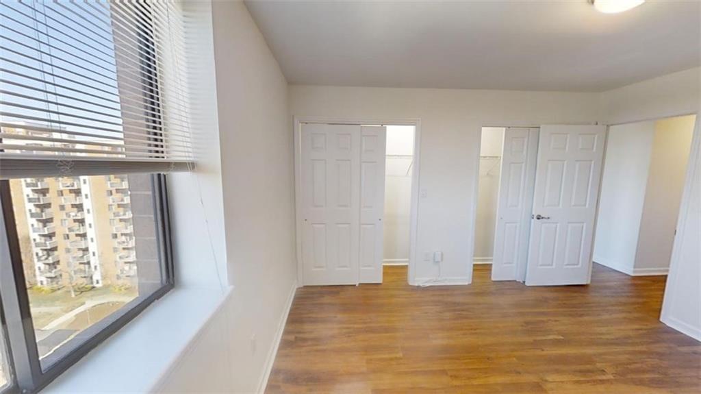 Unfurnished bedroom featuring multiple closets and hardwood / wood-style floors