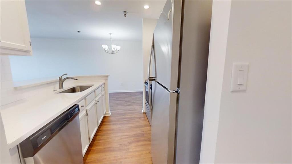 Kitchen featuring light hardwood / wood-style floors, white cabinets, a chandelier, stainless steel appliances, and sink