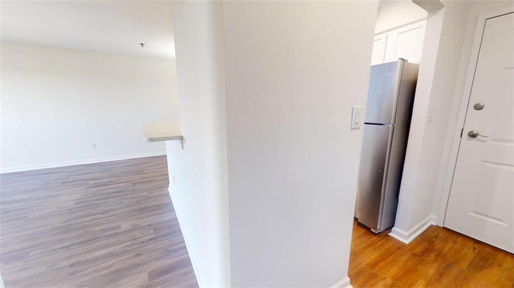 Kitchen with white cabinets, stainless steel refrigerator, and light hardwood / wood-style flooring