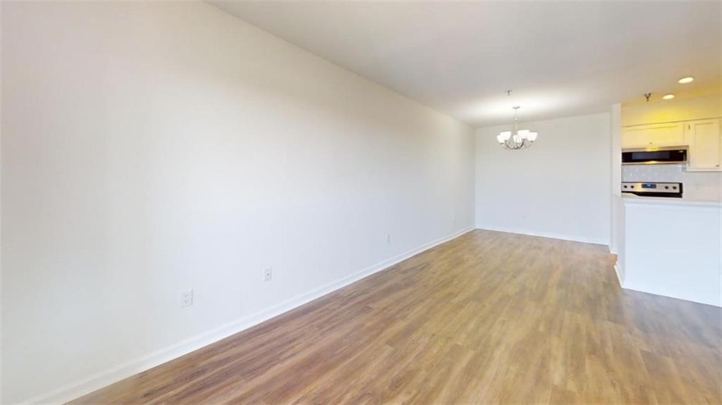 Unfurnished living room with an inviting chandelier and light wood-type flooring