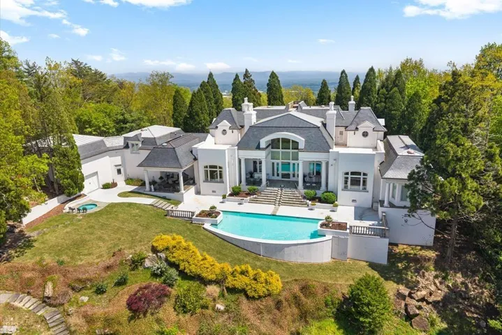 Stately multi-level residence with a white stucco facade and dark shingle roof