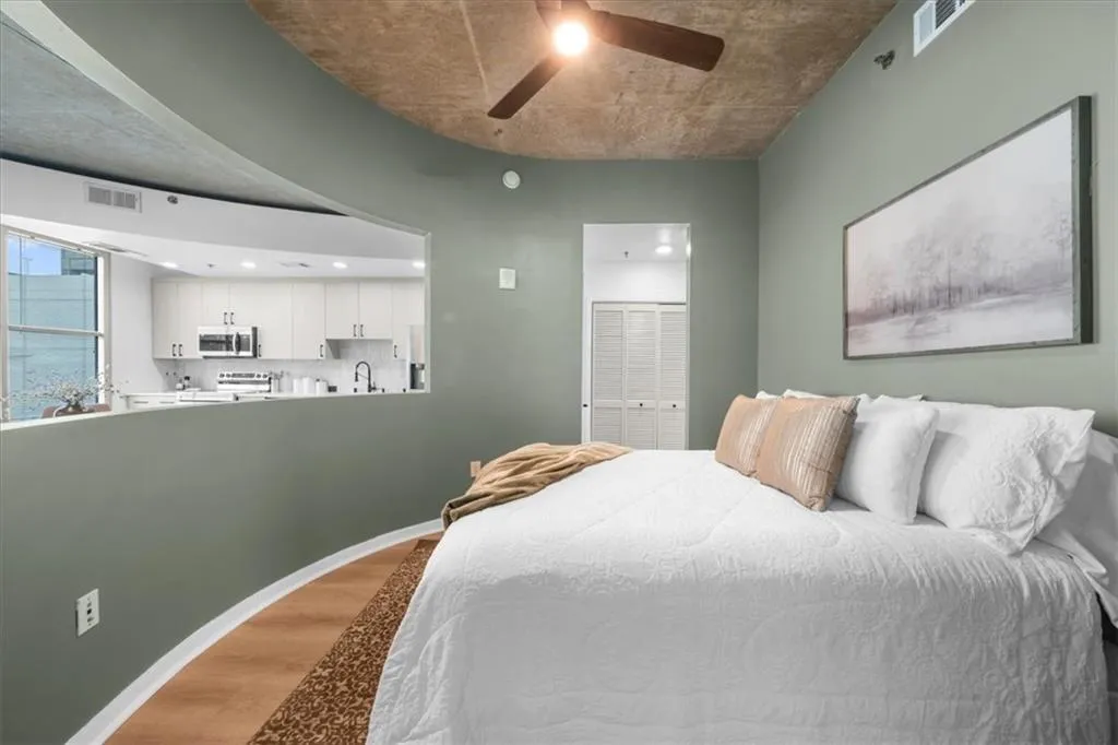 Bedroom featuring wide plank flooring and new ceiling fan - view to living room and Buckhead skyline sunsets