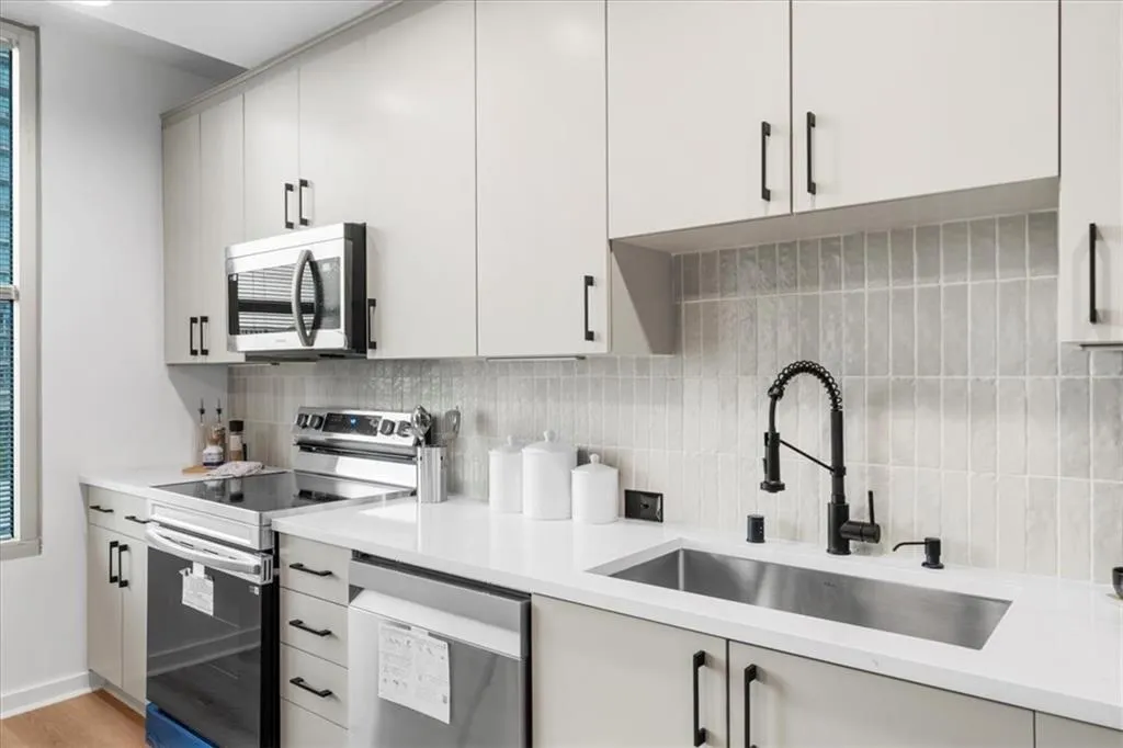 Kitchen featuring New Sink, Brand New Samsung appliances, Edward Martin tile backsplash, light stone countertops, and light oak wide plank wood flooring