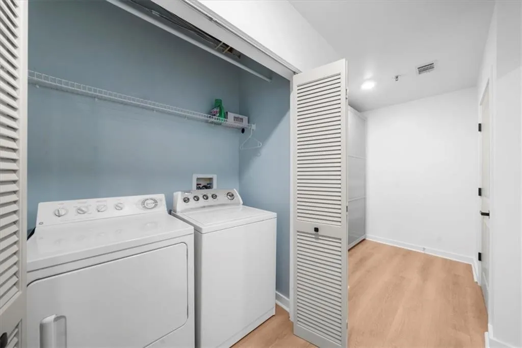 Laundry room featuring light wood-type flooring and washing machine and clothes dryer