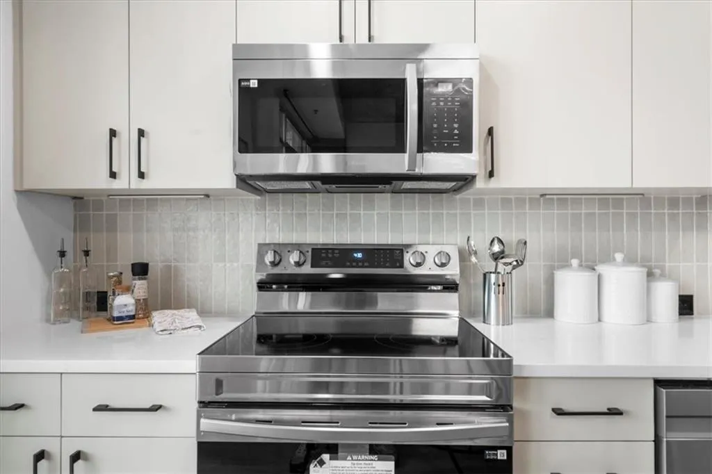 Kitchen featuring Brand New stainless steel Samsung appliances, white cabinets, and Edward Martin tile backsplash