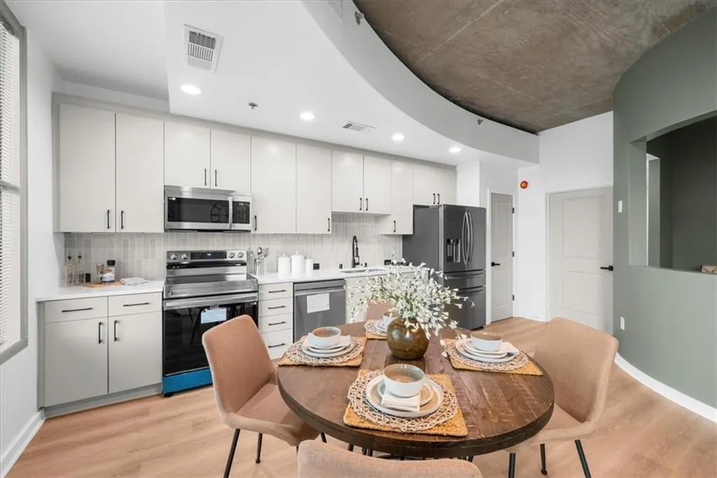 Kitchen with appliances with stainless steel finishes, tasteful backsplash, light wood finished floors, white cabinetry, and recessed lighting