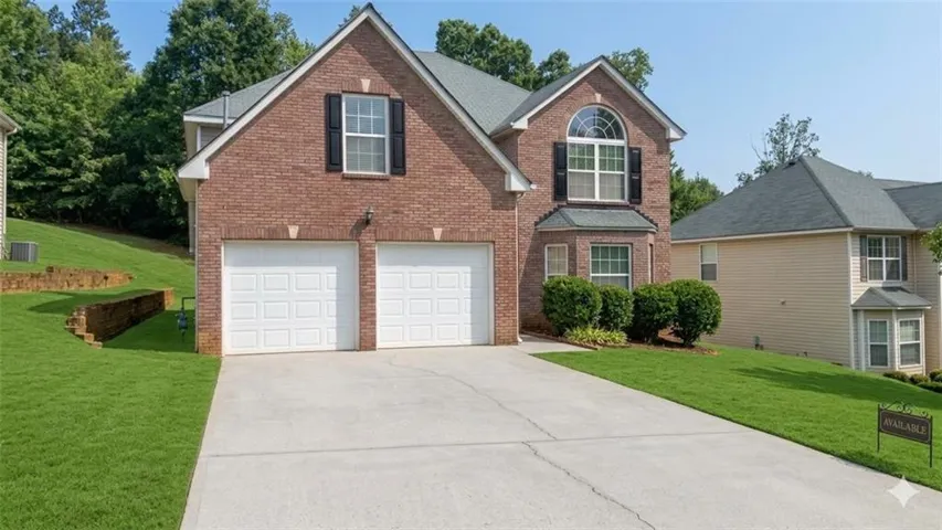 Traditional-style house featuring a front lawn, brick siding, driveway, and an attached garage