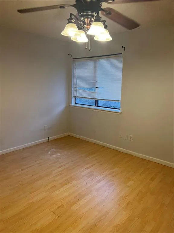 Spare room with light hardwood / wood-style flooring and ceiling fan with notable chandelier