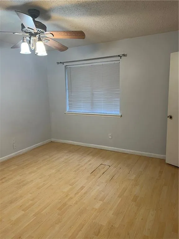Spare room featuring light hardwood / wood-style floors, a textured ceiling, and ceiling fan