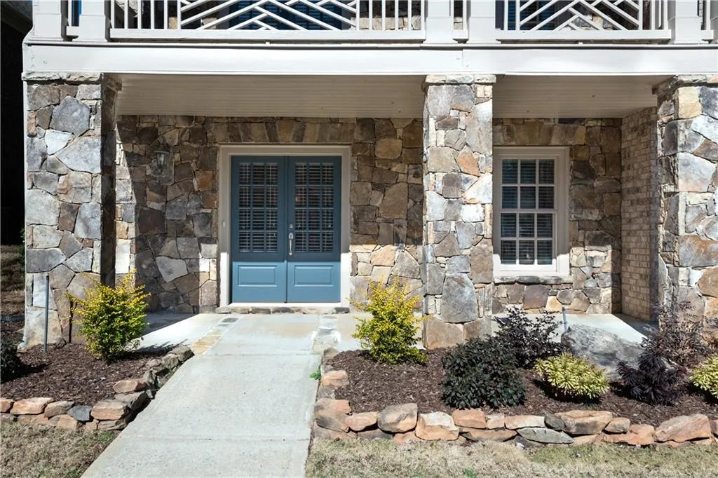 Entrance to property featuring stone siding, french doors, and a balcony