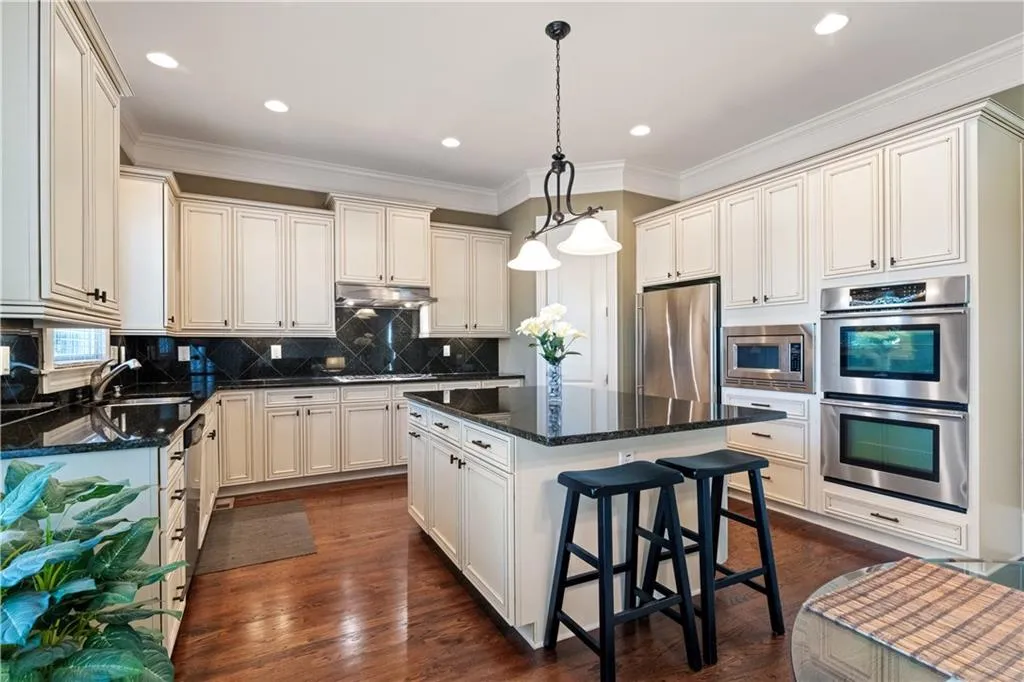Kitchen featuring decorative backsplash, a center island, stainless steel appliances, under cabinet range hood, and a sink
