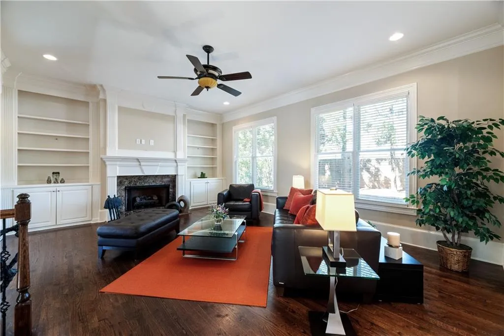 Living room featuring a fireplace, ornamental molding, dark wood-type flooring, and recessed lighting