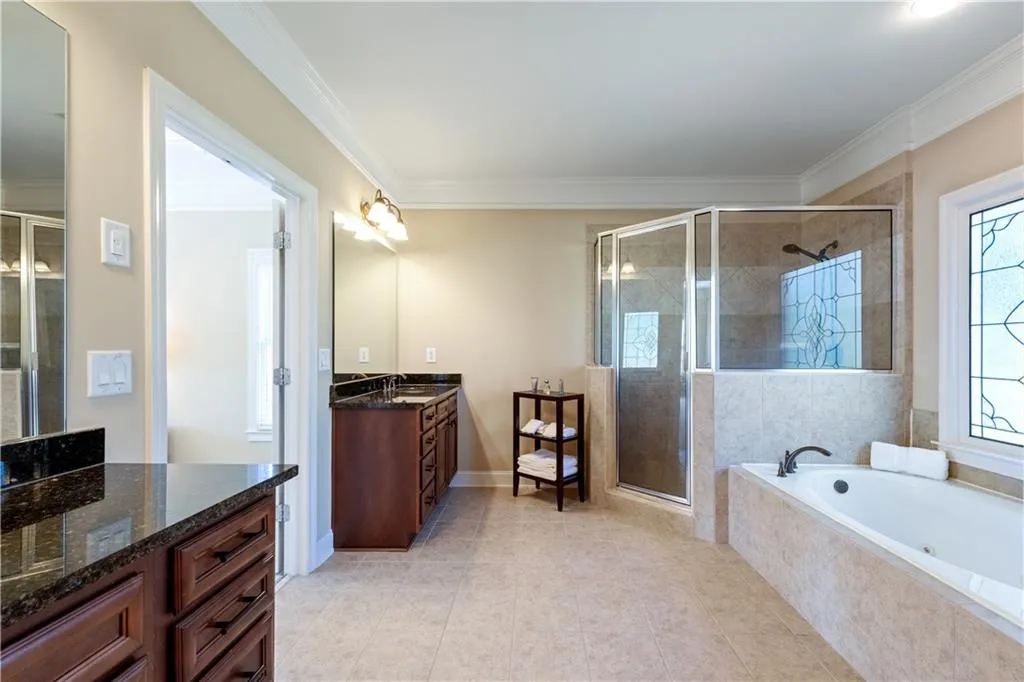 Full bath with ornamental molding, tile patterned flooring, vanity, a shower stall, and a bath