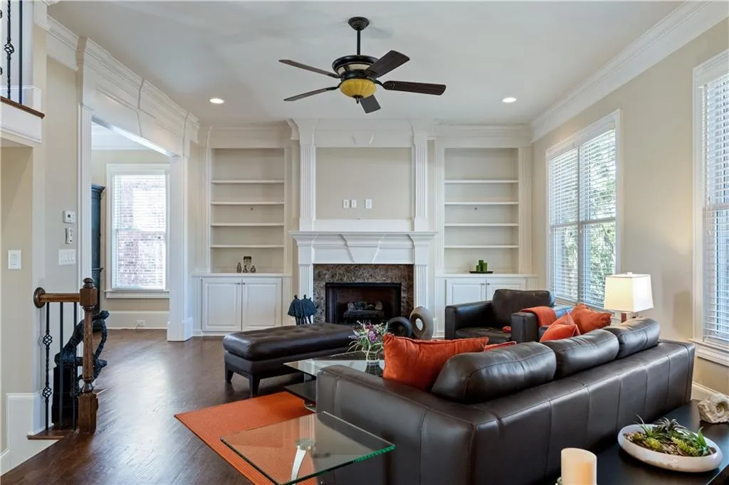 Living room with dark wood finished floors, ornamental molding, built in shelves, a fireplace, and recessed lighting