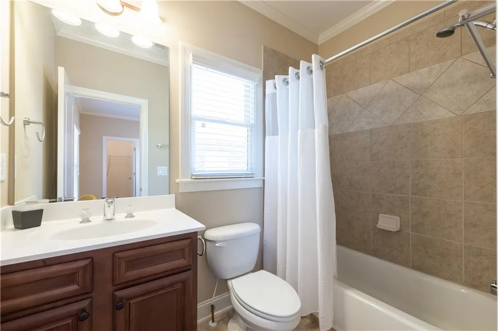 Full bath with toilet, shower / bathtub combination with curtain, crown molding, and vanity