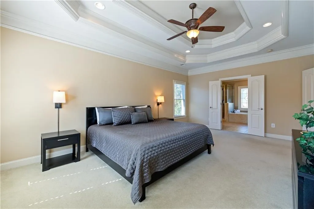 Bedroom with recessed lighting, light colored carpet, baseboards, ornamental molding, and a raised ceiling