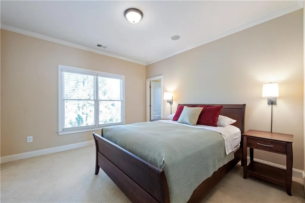 Bedroom with baseboards, visible vents, crown molding, and light colored carpet
