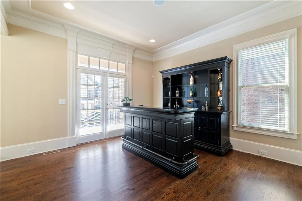 Bar featuring baseboards, visible vents, dark wood-type flooring, and crown molding