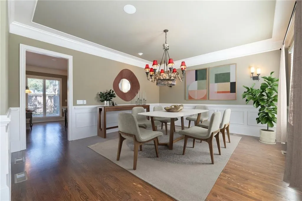 Dining area featuring a wainscoted wall, a decorative wall, ornamental molding, wood finished floors, and a chandelier