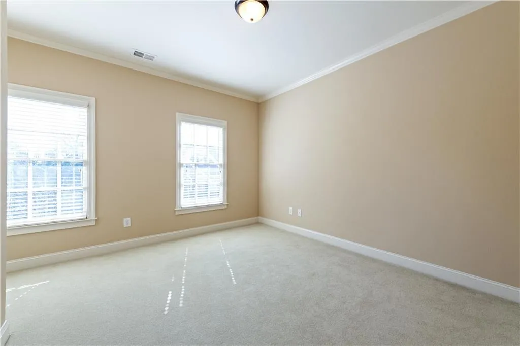 Spare room featuring ornamental molding, light colored carpet, and visible vents