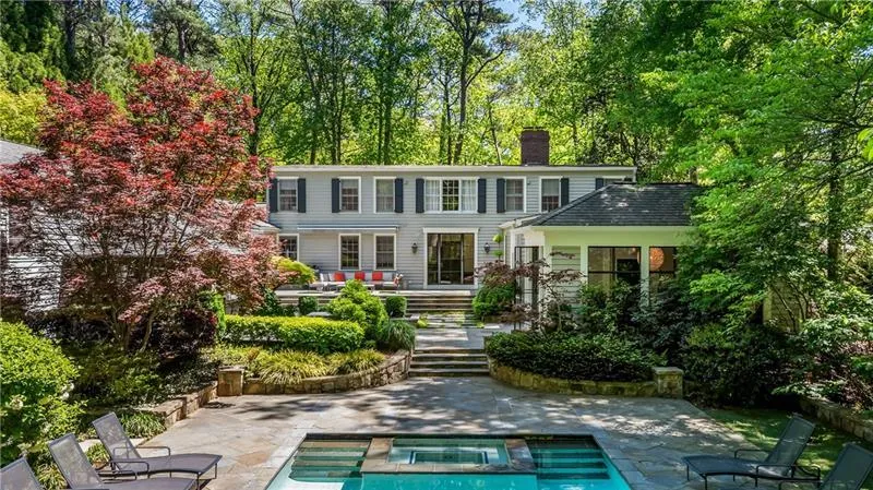 Rear view of house with a patio area, a chimney, a deck, and a pool with connected hot tub