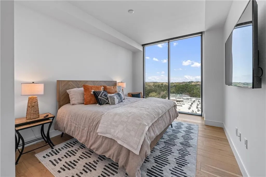 Bedroom with light wood-type flooring, a wall of windows, and access to outside