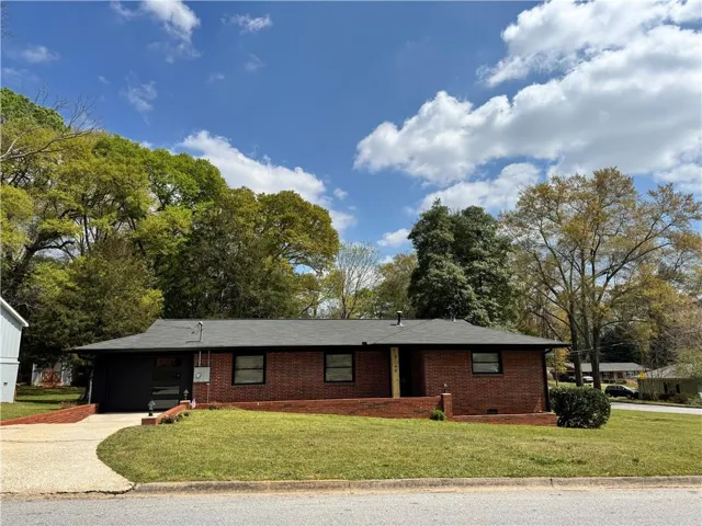 Ranch-style house featuring a front yard, brick siding, and concrete driveway
