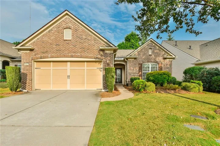 Brick exterior with architectural shingles, attached two-car garage, concrete driveway, and a curved walkway to the entry