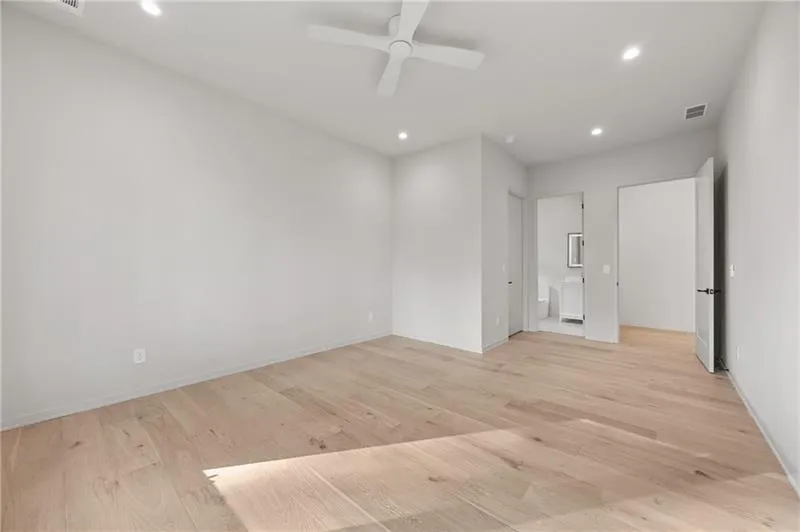 Unfurnished bedroom featuring connected bathroom, ceiling fan, light wood finished floors, and recessed lighting