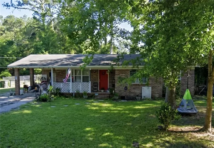 Brick exterior with a covered front porch, white lattice accents, and a paved driveway
