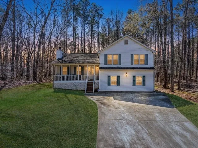 Two-story home featuring a covered front porch with white railing, a gabled roof, and a concrete driveway