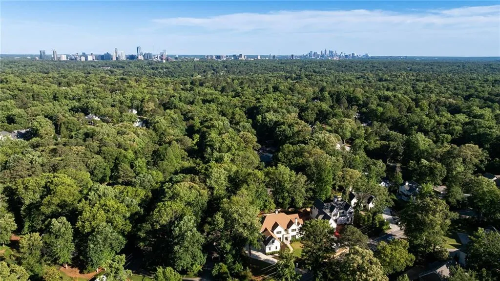 Aerial view of property and surrounding area featuring a forest and city skyline