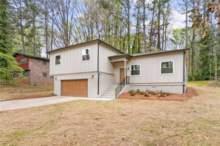 Contemporary exterior with light gray siding, a wood-finish garage door, and a covered entry