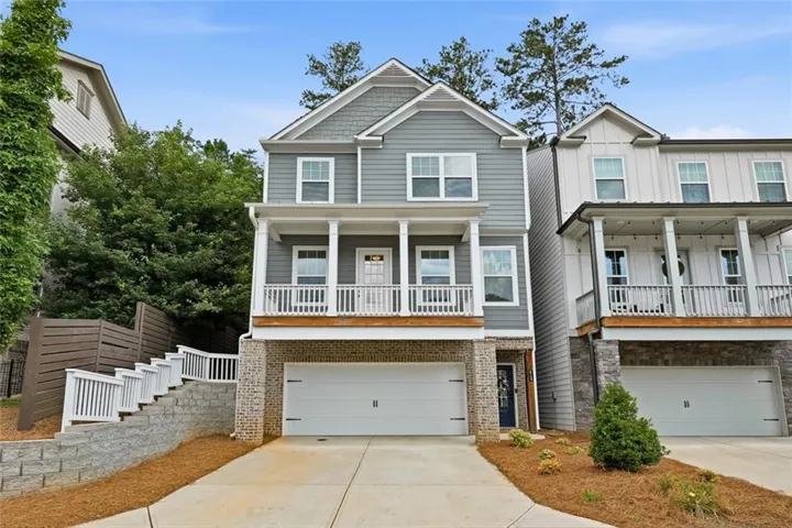 Contemporary residence featuring a two-car garage, stone and siding facade, and a covered balcony