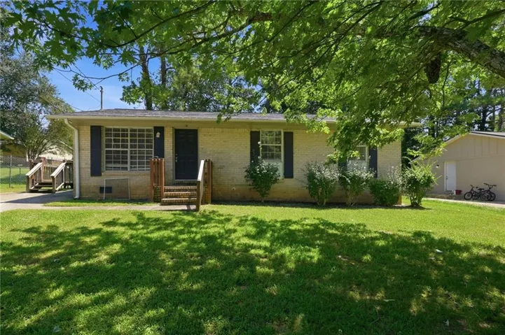 Brick exterior with dark shutters, front entry with wood steps and railing, and a manicured lawn