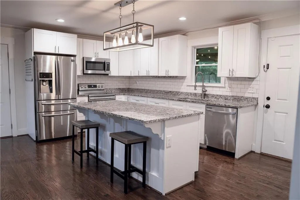 Kitchen featuring stainless steel appliances, white cabinets, tasteful backsplash, a center island, and recessed lighting