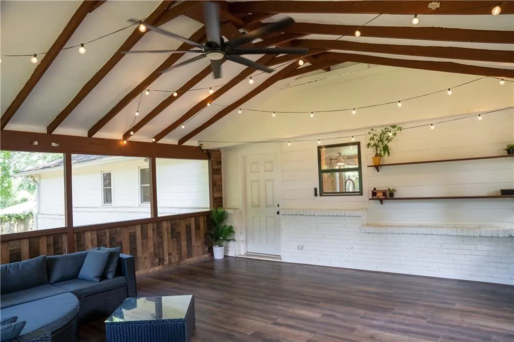 Unfurnished living room featuring wood finished floors, wooden walls, a ceiling fan, and brick wall