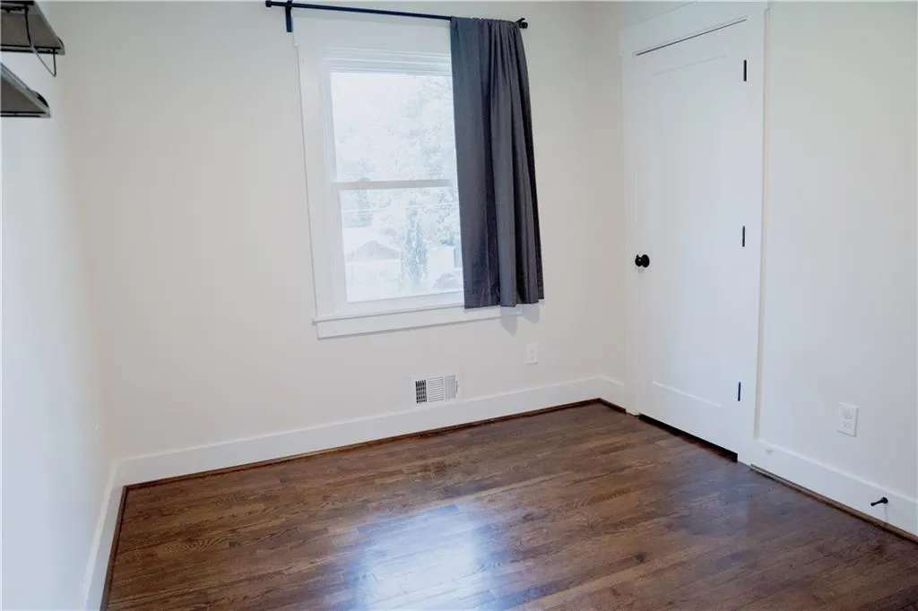 Unfurnished bedroom featuring dark wood-type flooring and baseboards