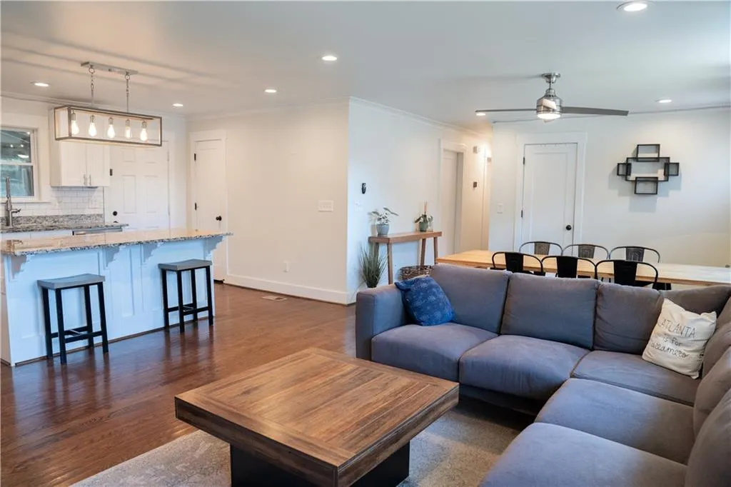 Living area with crown molding, recessed lighting, dark wood finished floors, and ceiling fan