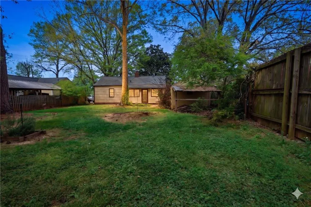 The property features an extensive yard with a lawn, a wooden privacy fence, and mature trees