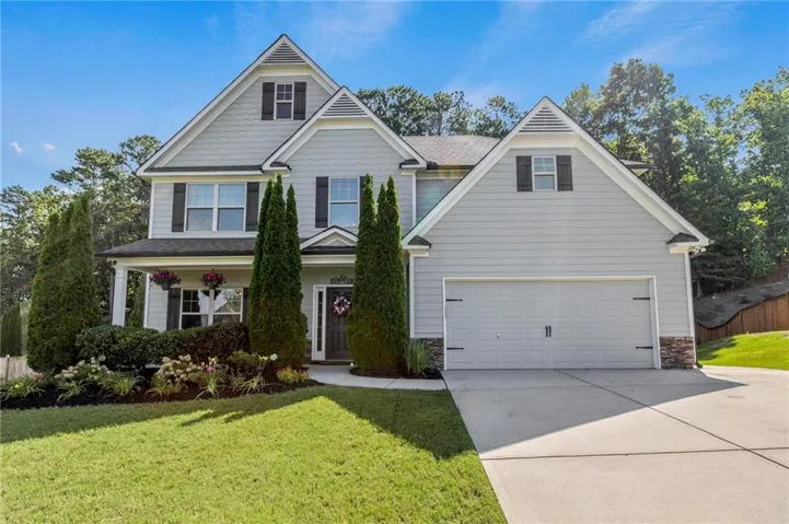 Two-story residence featuring light gray siding, dark shutters, and a covered front porch