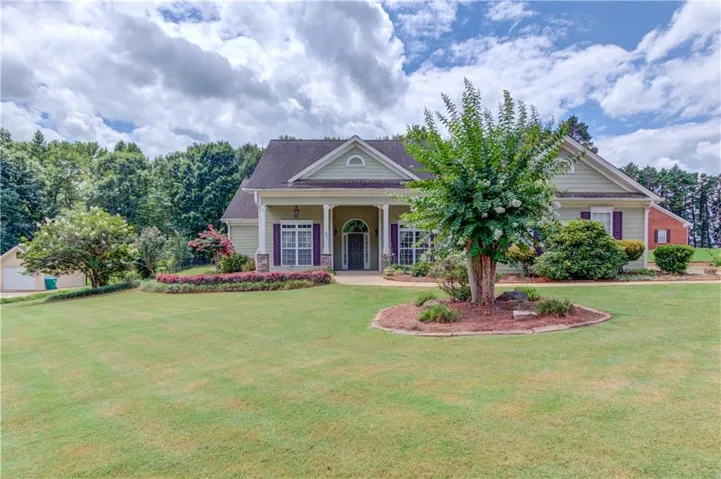 Elegant brick Colonial home featuring a covered entry portico with arched doorway, shuttered windows, and a side-entry garage
