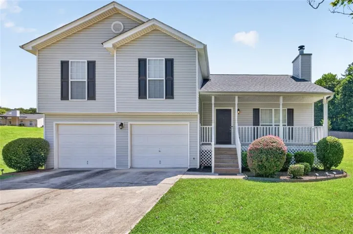 Siding exterior featuring a covered front porch, two-car garage, and mature landscaping